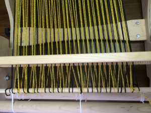 See how the strands behind the heddle are crossing over each other rather than going straight through each slot or eye?