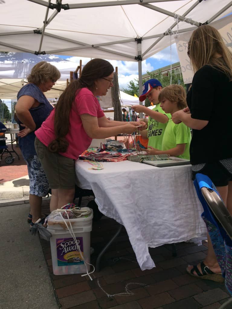 WoO members Nancy (foreground) and Bev teaching Kumihimo braiding to Festival attendees on Saturday.